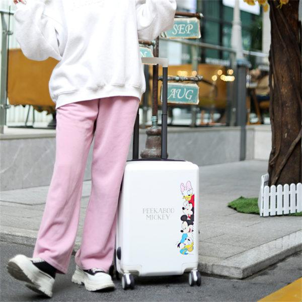 Person with white Mickey and Friends suitcase, emphasizing travel-ready style for IP-licensed partnerships