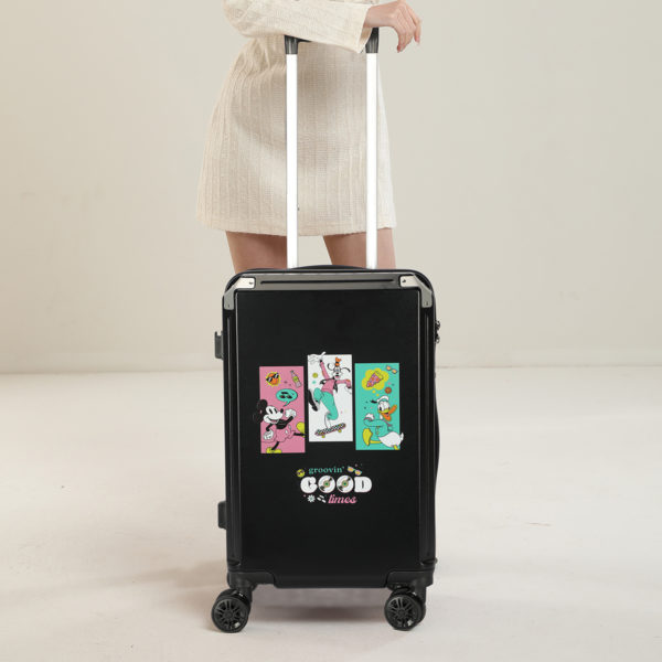 Model with a 24 - inch black Disney suitcase featuring “groovin’ GOOD times” graphics, ideal for Disney IP - licensed wholesale
