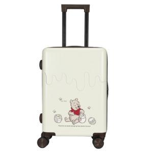 A 24-inch white suitcase featuring a Winnie the Pooh illustration with honey pots and the quote "There's no such thing as too much honey."